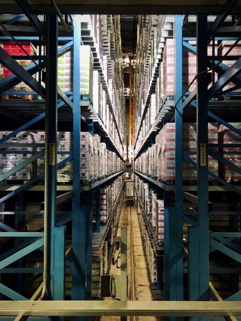 A narrow space between tall, blue warehouse shelves